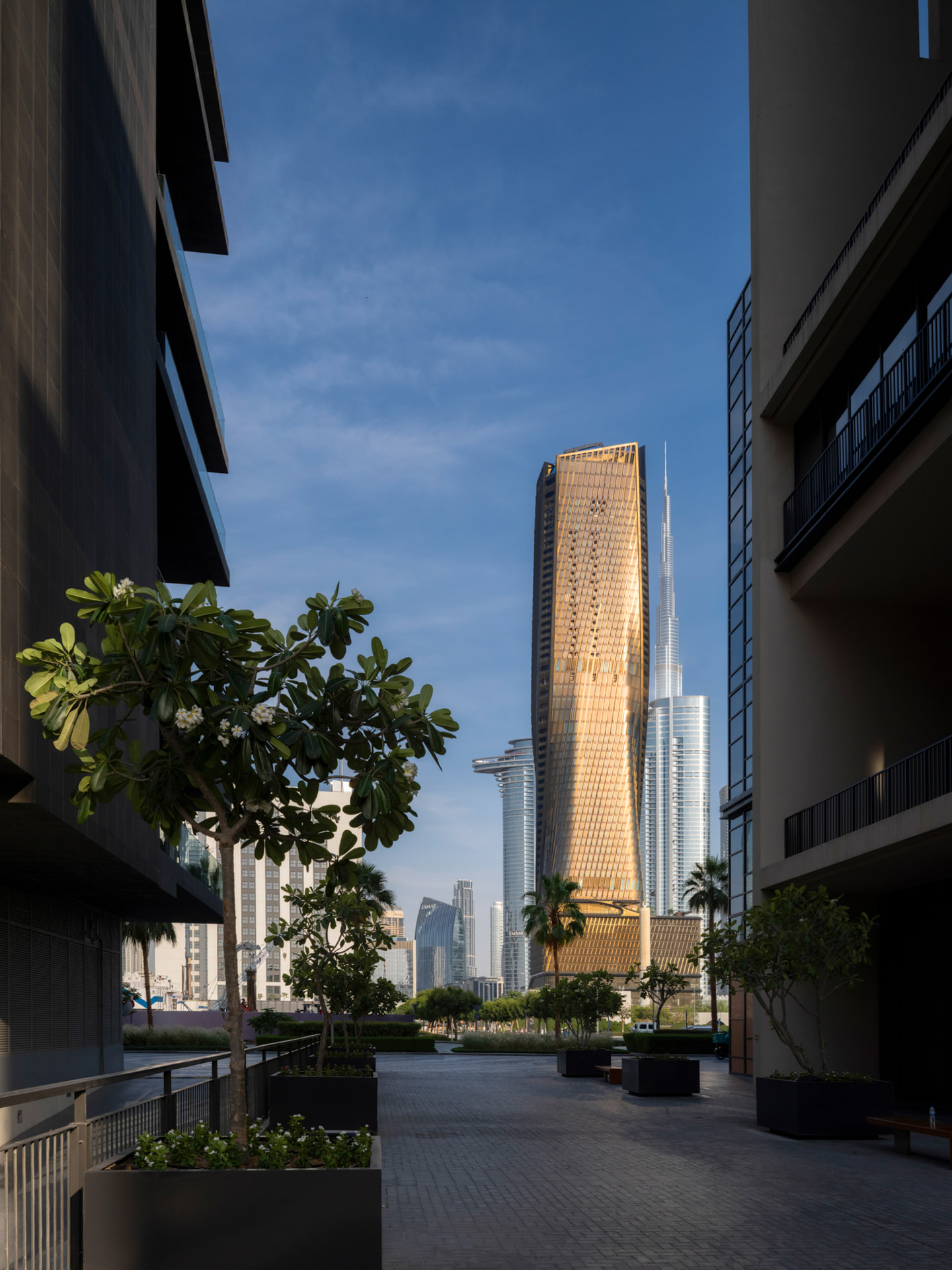 Framed plaza and alley composition showing Wasl Tower with Burj Khalifa behind
