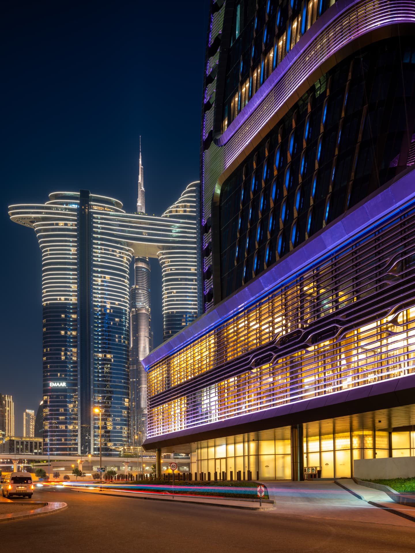 Night street-level view of Wasl Tower's illuminated podium against the Dubai skyline
