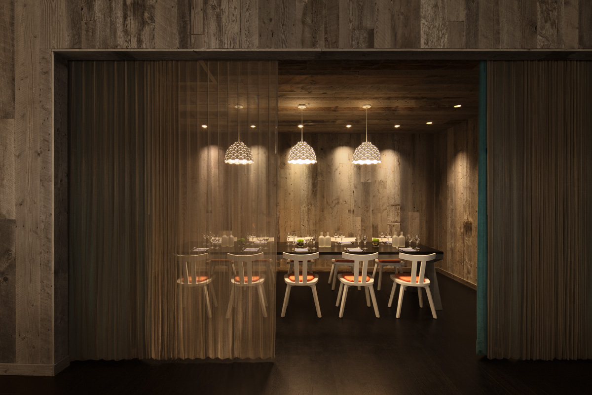 Chef's table at Rosewood Moscow set for service beside the open kitchen under focused pendant lighting