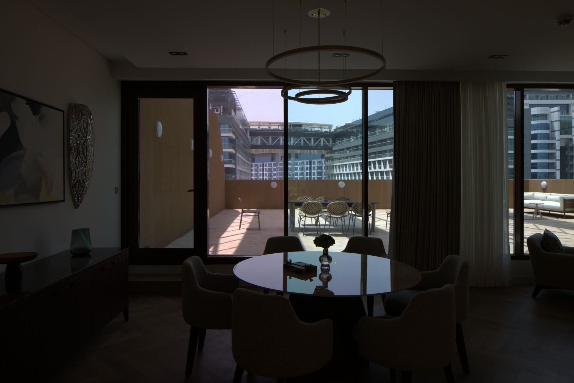 Cheval Maison The Palm dining room before the photography refresh — dimly lit interior with dark dining table and chairs, recessed ceiling lights and terrace visible through sliding glass doors