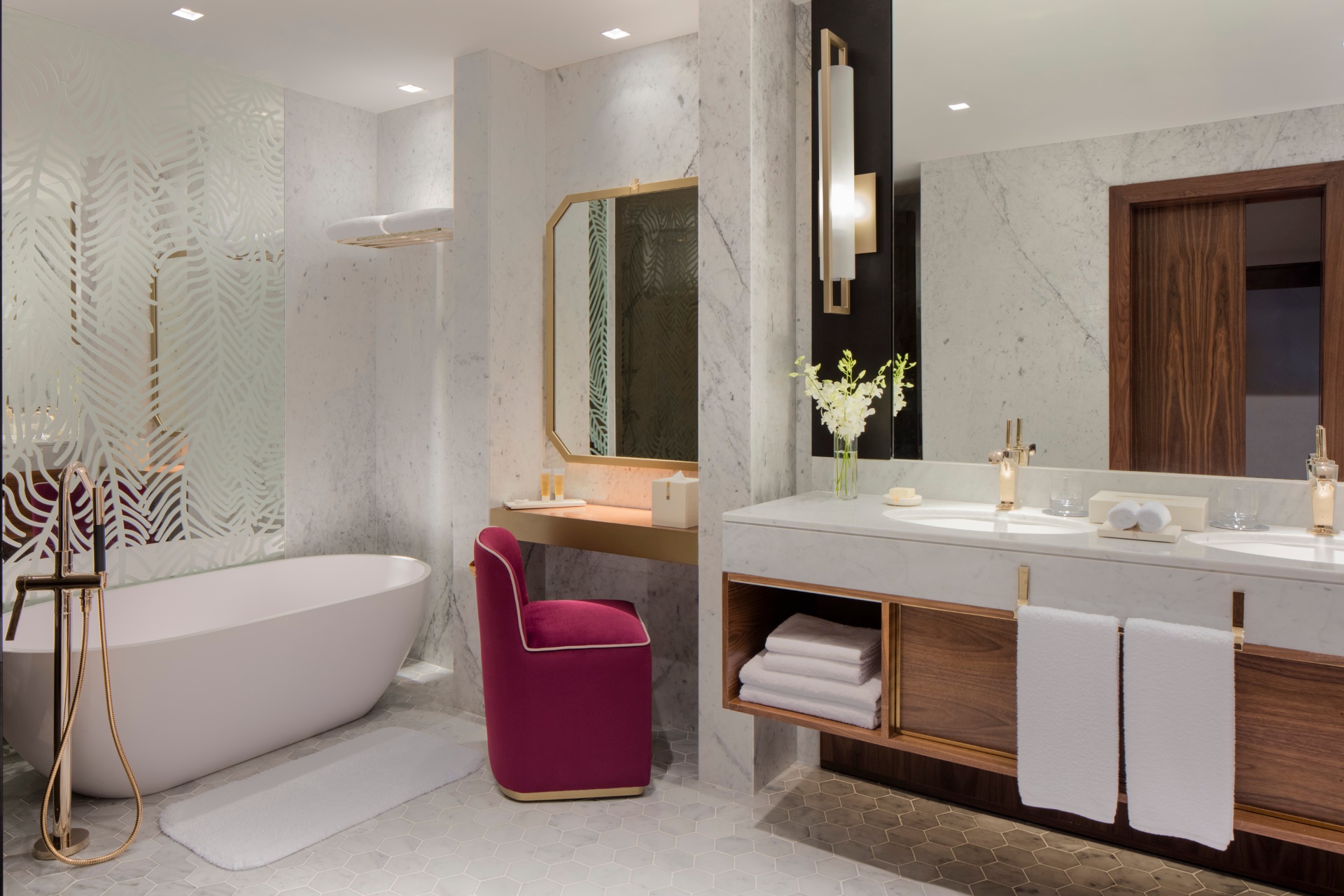 Master bathroom at Grand Hyatt Doha with deep bathtub, stone surrounds and folded towels in daylight