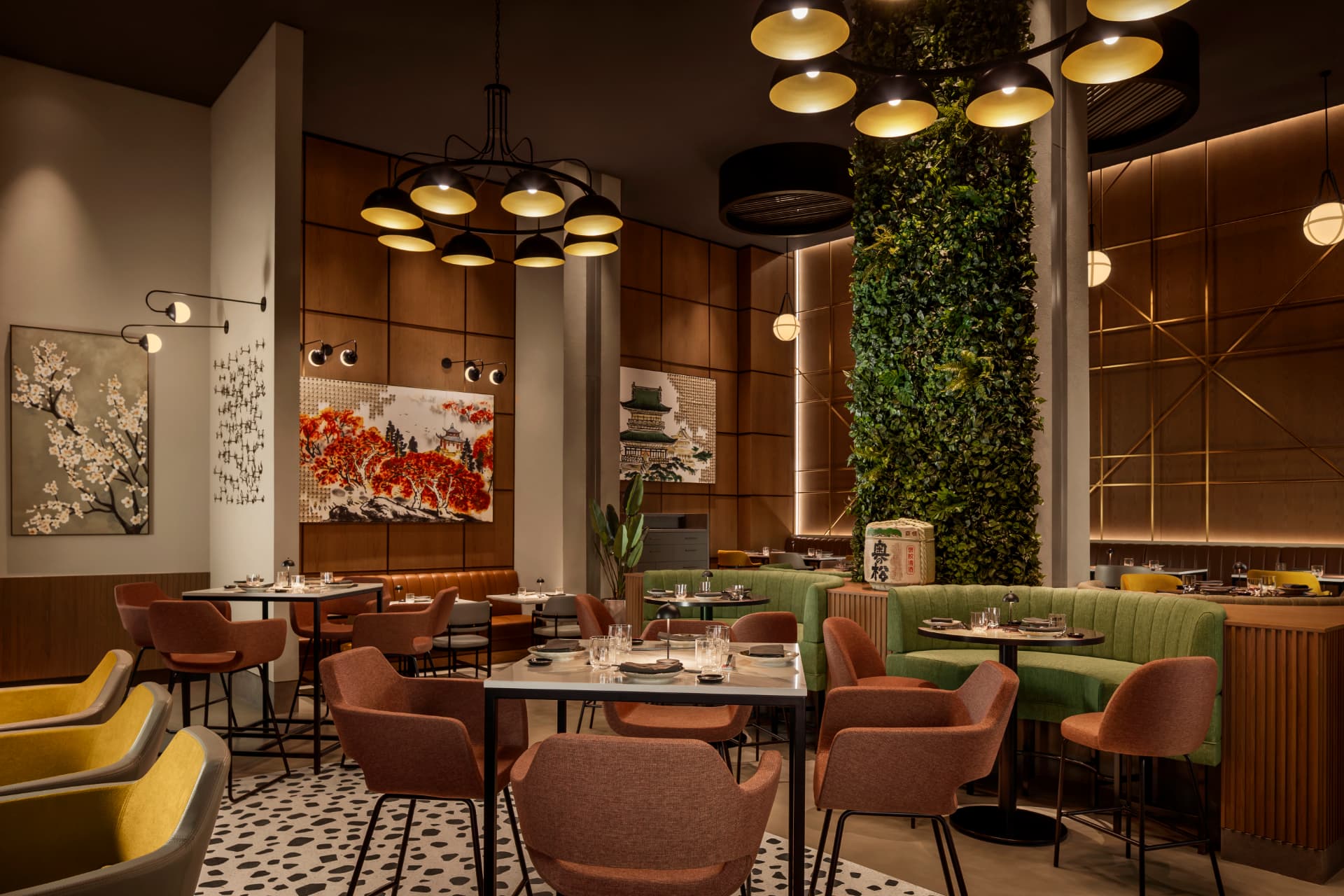 Yoru Japanese restaurant at Rotana Ras Al Khaimah after the refresh — warm pendant clusters, timber panelling, Japanese artwork, living green column and terracotta and green dining seating